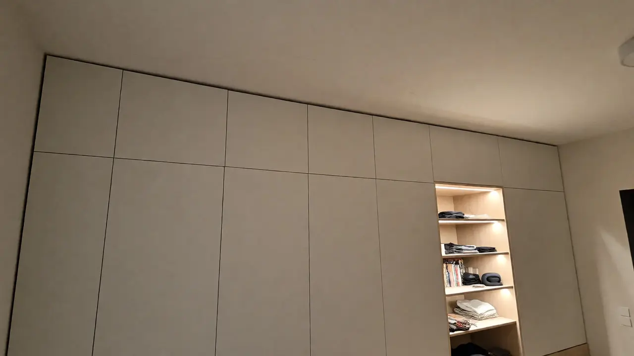 Meuble sur mesure intégré au mur avec éclairage LED et panneaux de finition discrets.